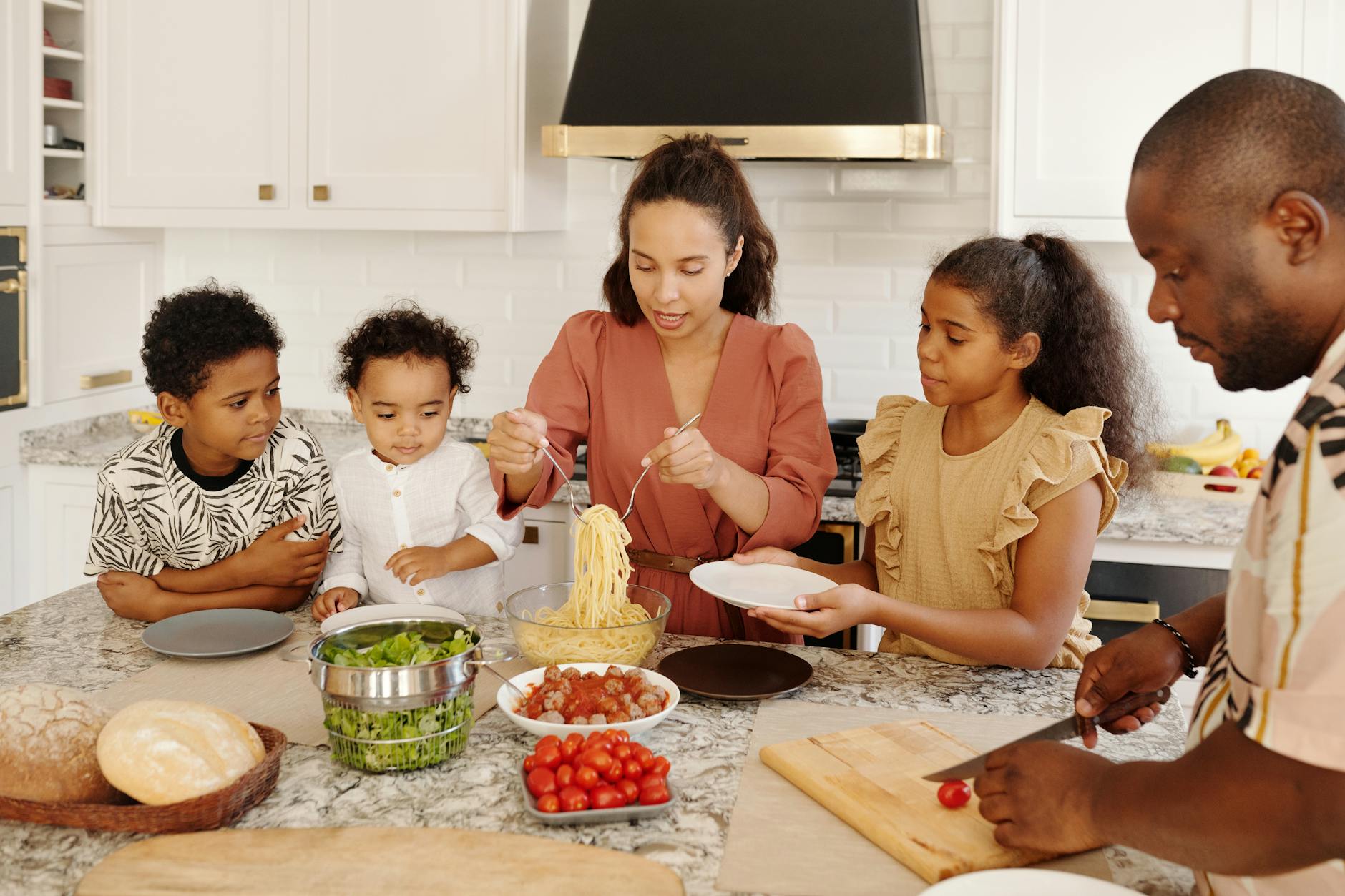Family cooking together in a modern kitchen, preparing pasta and vegetables with smiles and lively interaction.