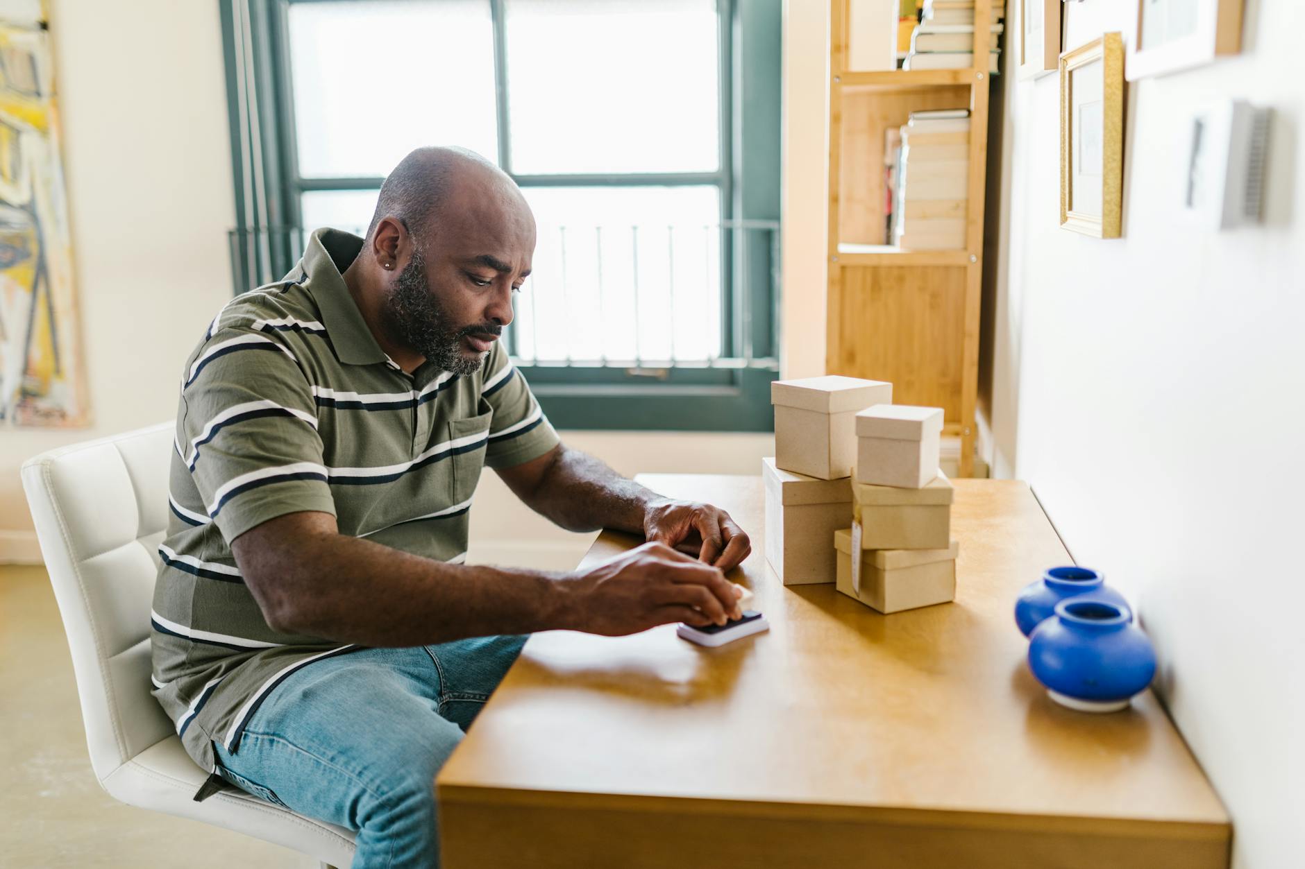 Bearded man at a home office desk, packing boxes for a small business startup.