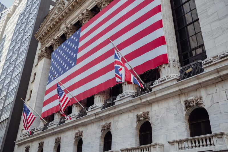 American flag waving on the facade of a historic building, showcasing architectural details and patriotic colors.