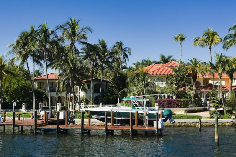 Luxury waterfront homes with palm trees and a docked boat in Fort Lauderdale, Florida.
