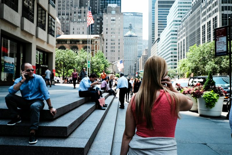 Busy New York City street filled with people, surrounded by iconic skyscrapers under bright daylight.