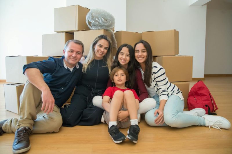 Joyful family sitting on the floor surrounded by moving boxes in their new home.