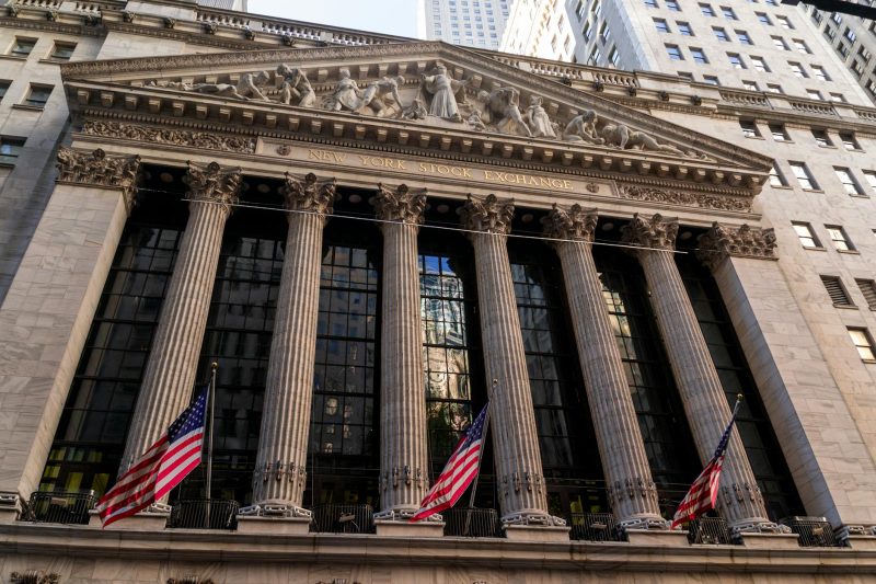 Neoclassical facade of the New York Stock Exchange adorned with American flags.
