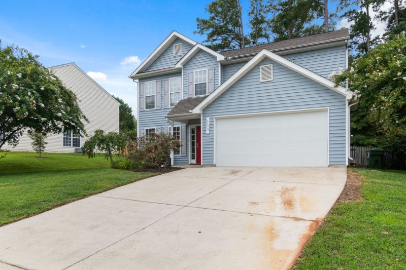 Charming two-story suburban home surrounded by greenery and a spacious driveway.