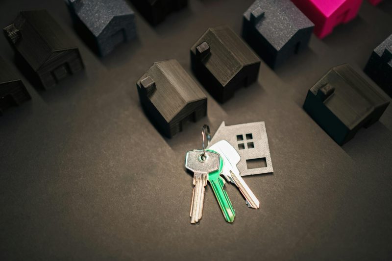 Miniature house models beside key replicas representing real estate investment and the housing market.