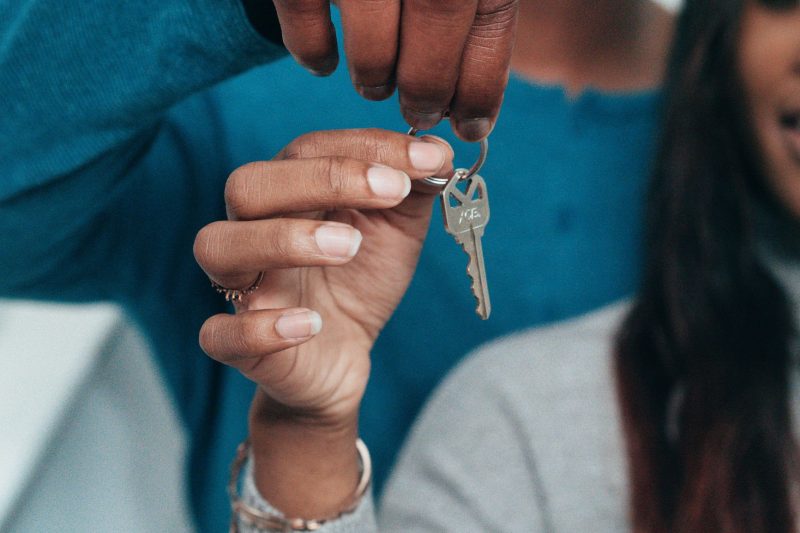 A couple joyfully holding a key, representing their new home ownership.