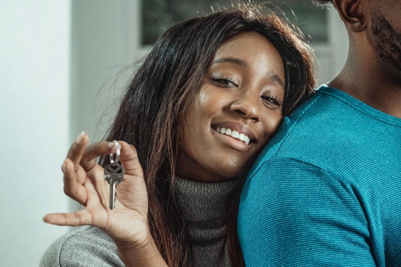 Joyful couple holding house keys, smiling together, celebrating their new home purchase.