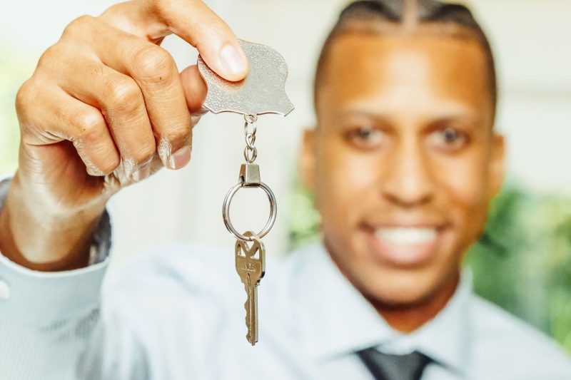 A smiling real estate agent holds out a key, symbolizing a new home purchase.