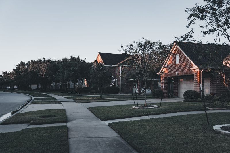 Serene suburban scene with brick houses and well-manicured lawns at dusk.
