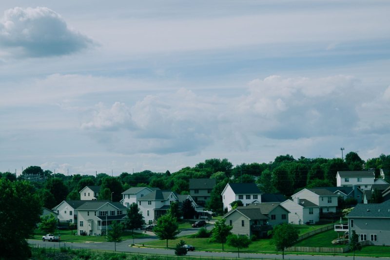 Picturesque suburban houses with well-manicured lawns under a blue sky dotted with clouds in Wisconsin.