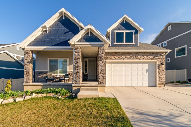 Charming modern suburban home with a stone facade and well-maintained lawn.