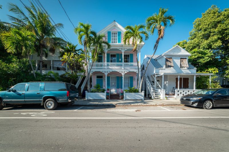 Colorful historic houses and palm trees line a sunny street in Key West, Florida.